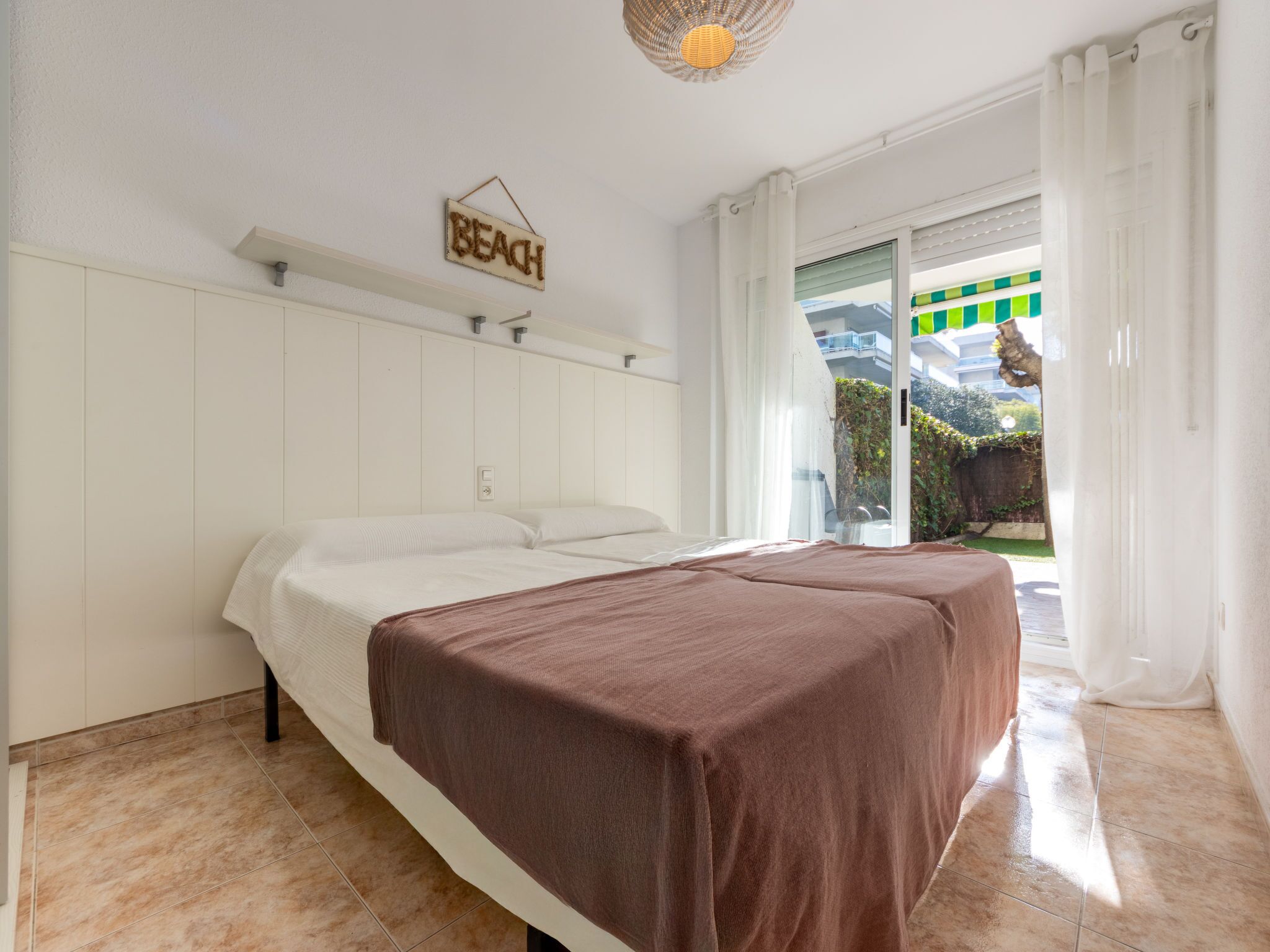 Une chambre avec un lit, un panneau indiquant « PLAGE » et une vue sur un jardin.