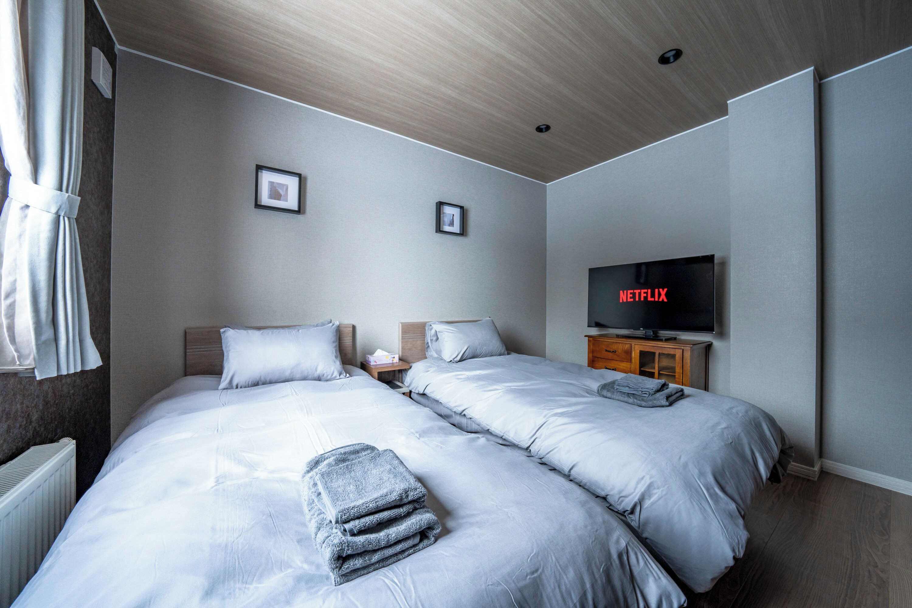 A hotel room with two beds, a TV, and a wooden ceiling.