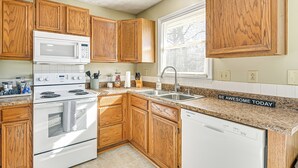 Une cuisine avec des meubles en bois, une cuisinière blanche, un four à micro-ondes et un lave-vaisselle.