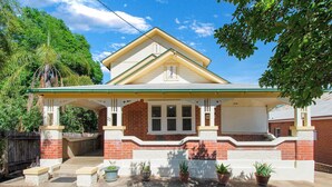 A two-story house with a covered porch, brick exterior, and a well-maintained lawn.
