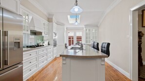A spacious kitchen with white cabinetry, a central island, and a stainless steel refrigerator.