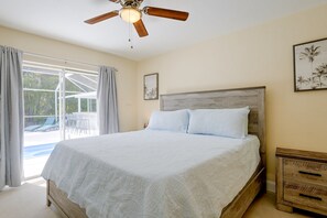 A bedroom with a bed, a ceiling fan, a window with curtains, and a view of the outdoors. - Hot Tub & Outdoor Pool: Bonita Springs Getaway! (Bonita Springs)
