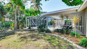 A modern house with a covered patio, a swimming pool, and lush greenery. - Hot Tub & Outdoor Pool: Bonita Springs Getaway! (Bonita Springs)