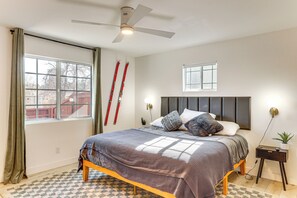A bedroom with a bed, a ceiling fan, a window, and a nightstand with a lamp. - Fish, Hike & Explore: Cabin w/ Yard in Big Bear (Big Bear)