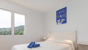 A bedroom with a bed, a window, and a wall art piece.