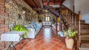 Ein rustikaler Innenraum mit Steinwand, Holztreppe und gefliestem Boden.