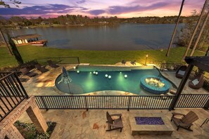 A swimming pool with a hot tub, surrounded by lounge chairs and a stone deck. - 7BR Lakefront Haven Pool Hot Tub Gated 4acres (Lizella)