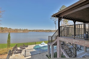 A lakeside property with a covered patio, outdoor seating, and a swimming pool. - 7BR Lakefront Haven Pool Hot Tub Gated 4acres (Lizella)