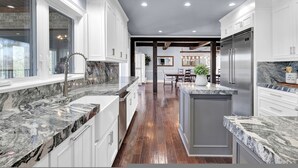 A modern kitchen with white cabinetry, granite countertops, and a central island.