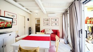 A modern living room with a dining table, red sofa, and artwork on the walls. - Casa Zivula: A welcoming apartment situated at a short distance from the waterfront, with Free WI-FI. (Olbia)