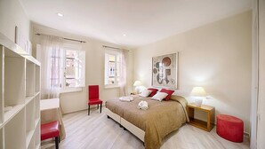 A hotel room with a bed, a chair, a small table, and a window with curtains. - Casa Zivula: A welcoming apartment situated at a short distance from the waterfront, with Free WI-FI. (Olbia)