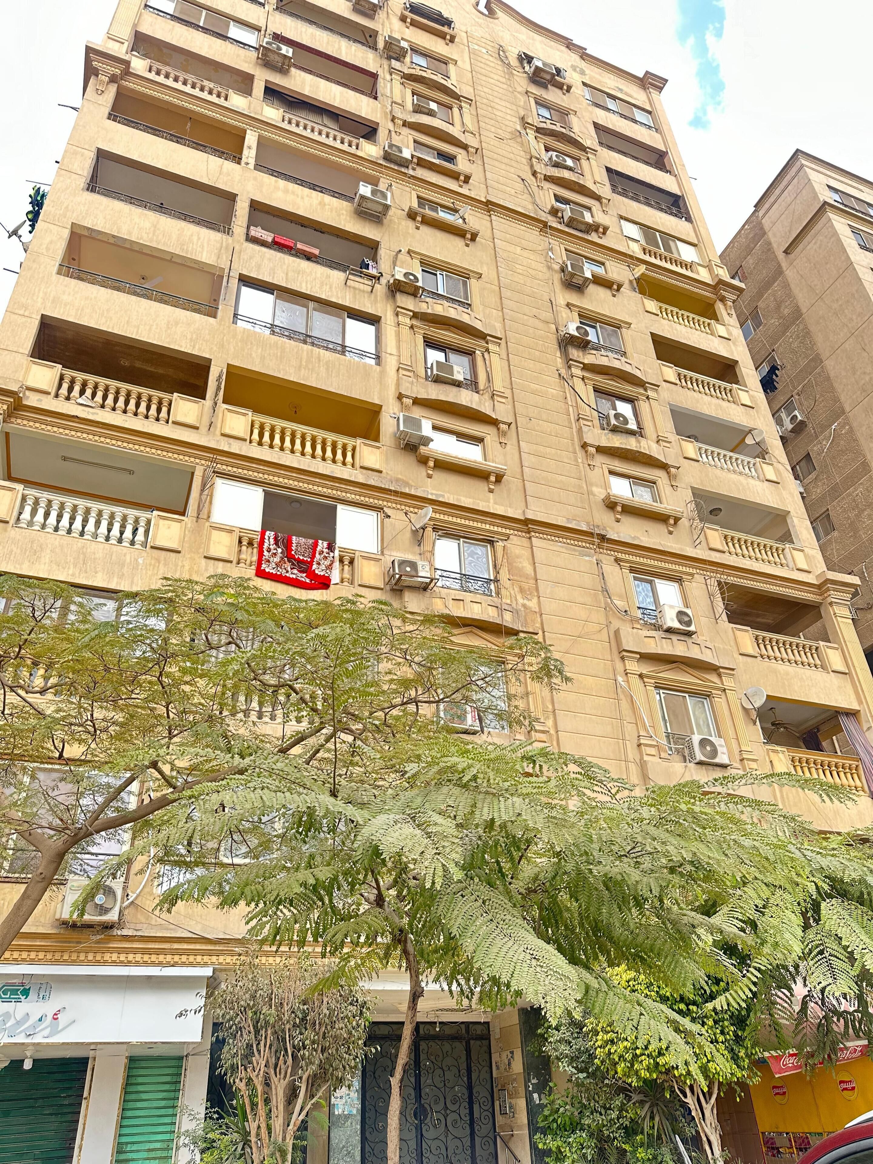 A multi-story building with balconies, air conditioning units, and a Coca-Cola sign.