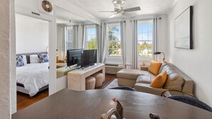 Una habitación de hotel moderna con cama, televisor, sofá y zona de comedor.