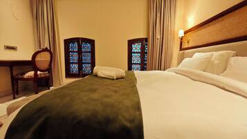 A hotel room with a bed, a desk, a chair, and two decorative screens with blue patterns.