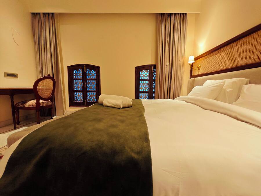 A hotel room with a bed, a desk, a chair, and two decorative screens with blue patterns.