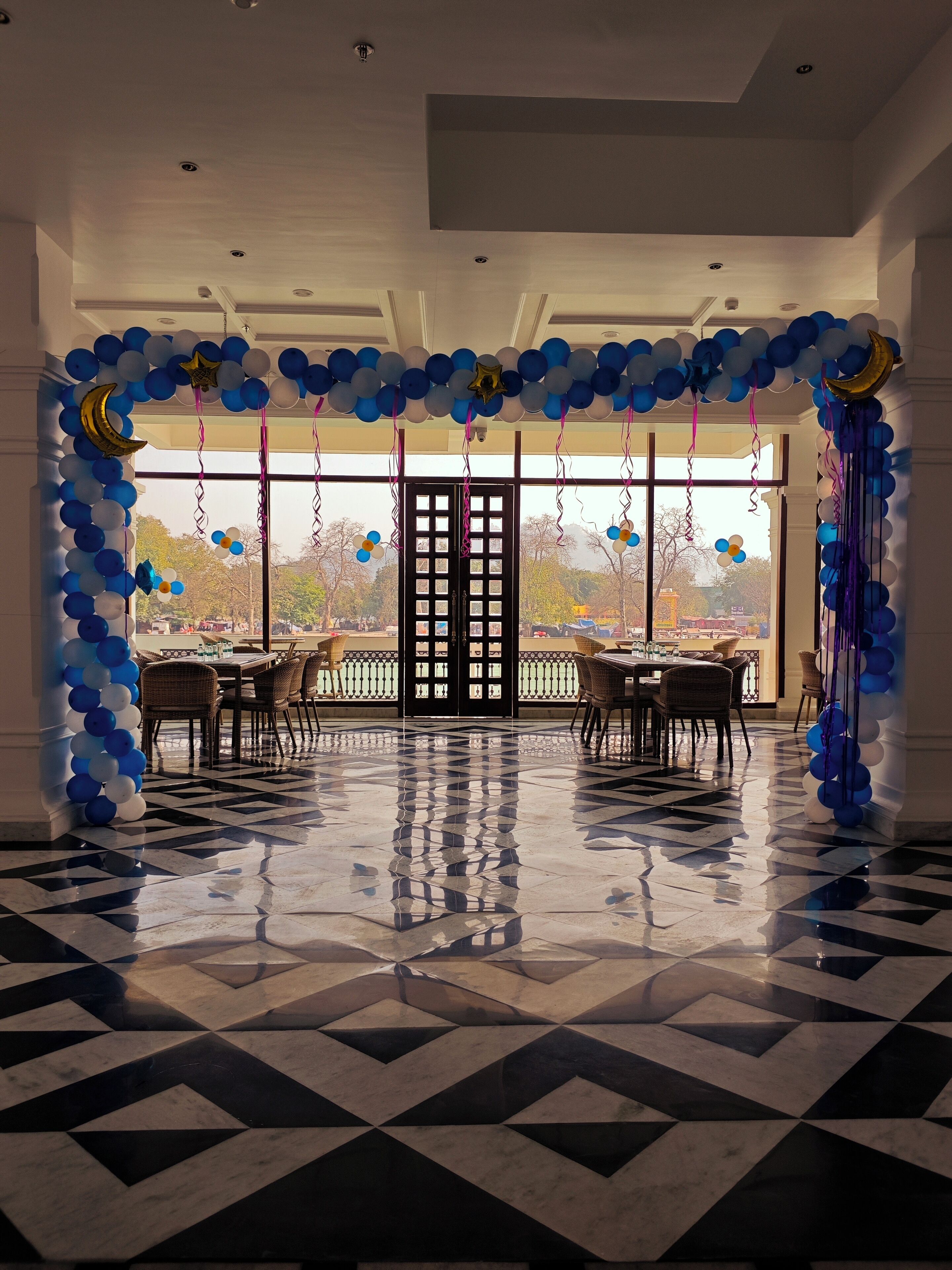 A spacious hall with a checkered floor, a large window, and a door with a grid pattern.