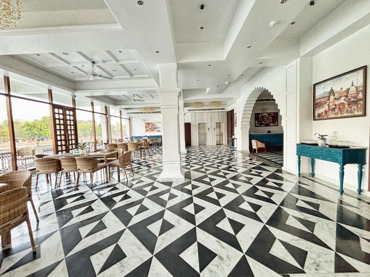 A spacious lobby with a geometric patterned floor, large windows, and a reception desk.