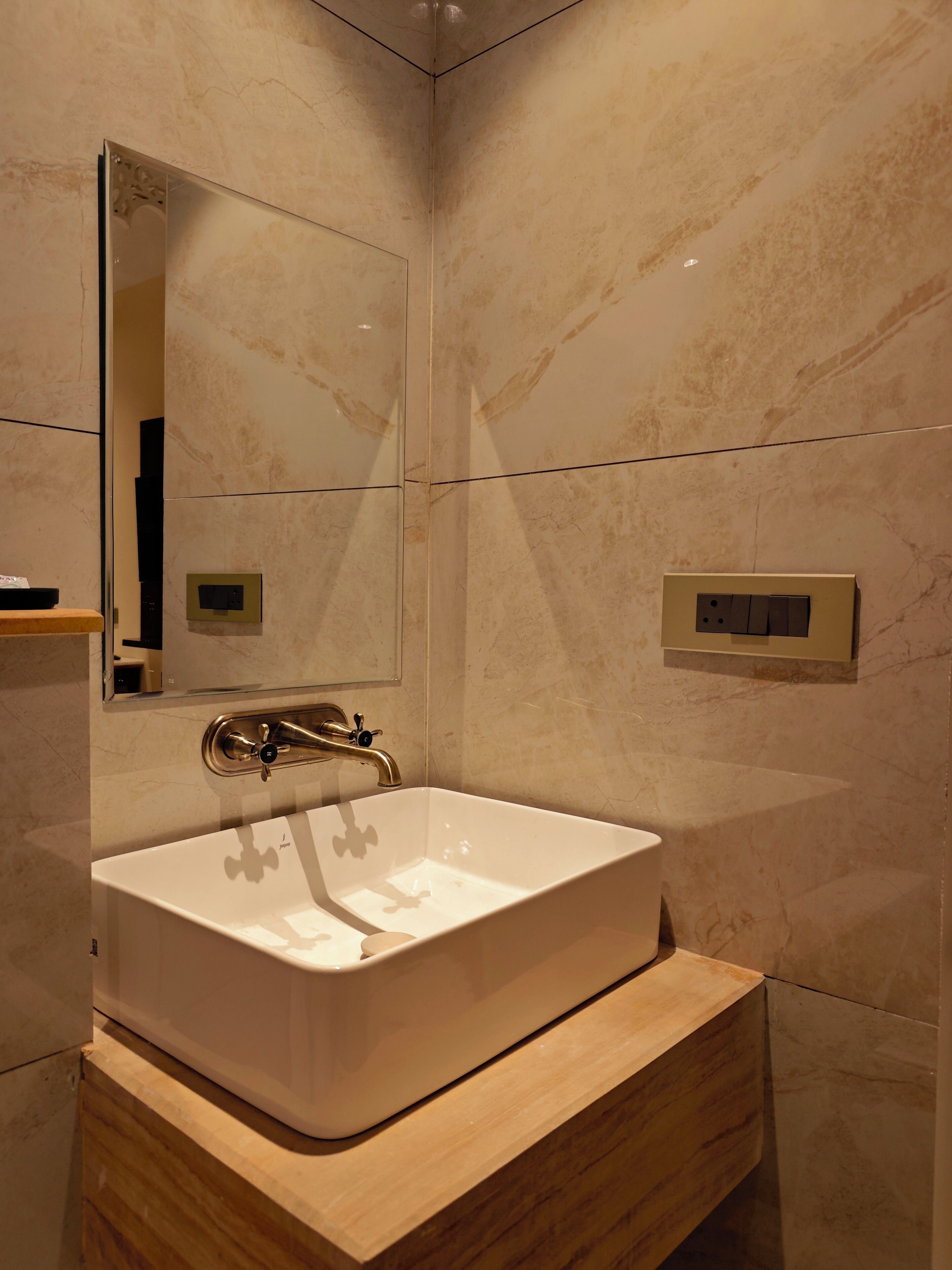 Un baño moderno con un lavamanos blanco, un espejo y un mueble de tocador de madera.