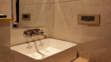 Un baño moderno con un lavamanos blanco, un espejo y un mueble de tocador de madera.