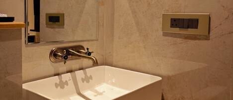 Un baño moderno con un lavamanos blanco, un espejo y un mueble de tocador de madera.