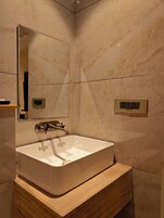 Un baño moderno con un lavamanos blanco, un espejo y un mueble de tocador de madera.