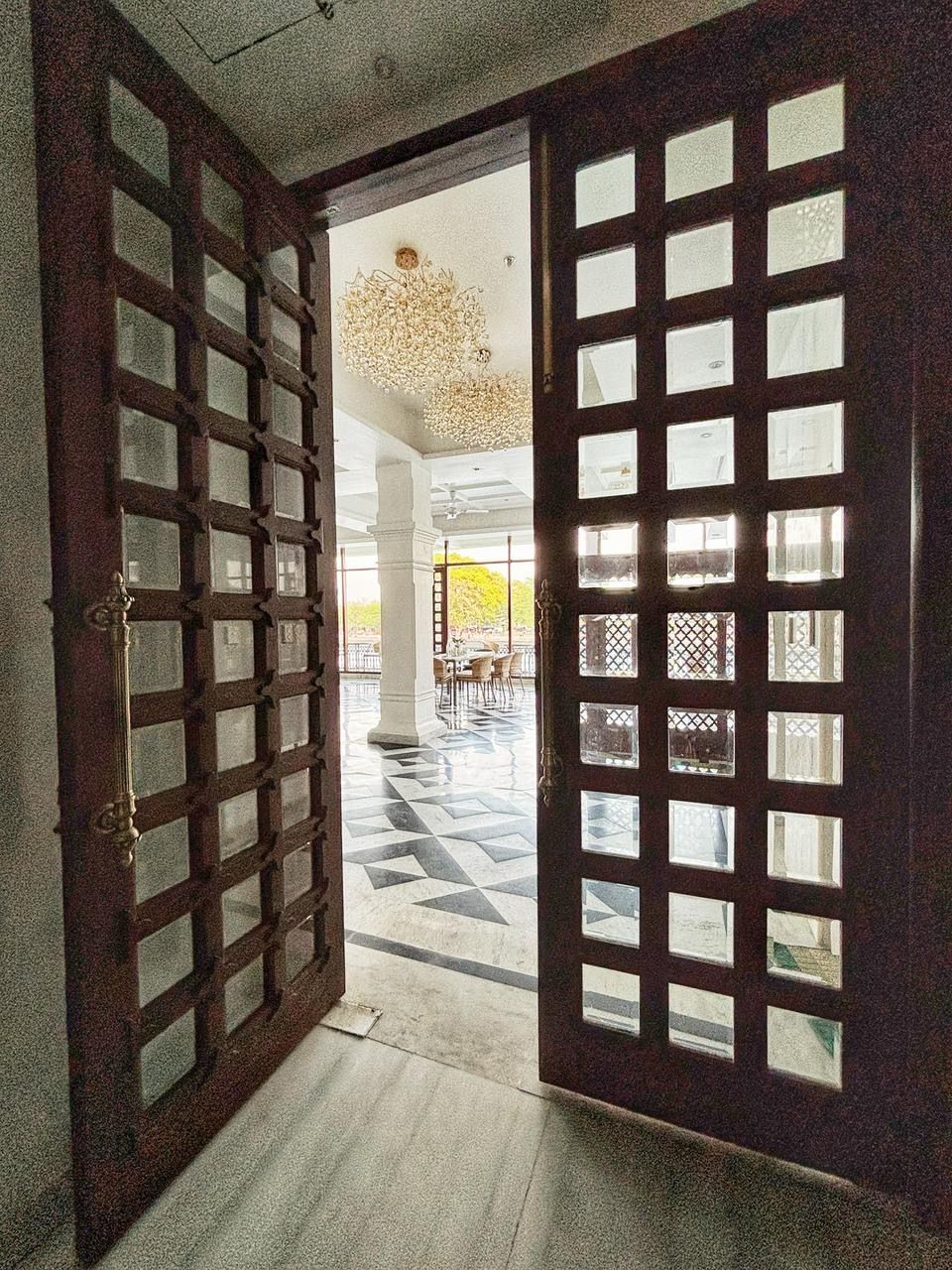 Un'imponente ingresso con una grande porta in legno decorata con un motivo a griglia e pannelli di vetro.