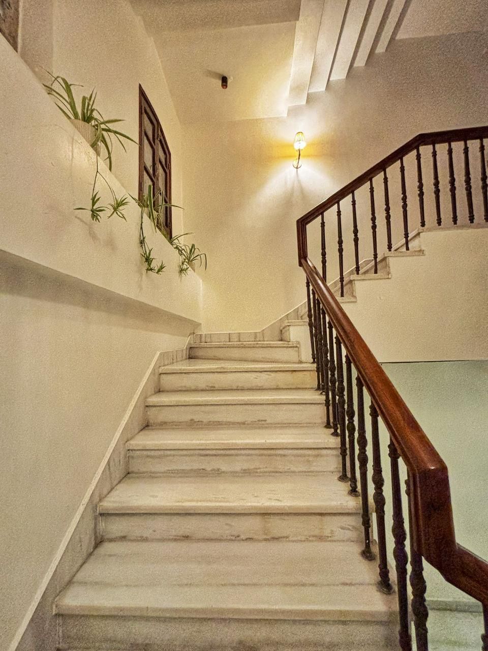 A staircase with a wooden handrail and a light fixture above it.