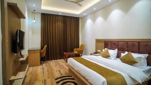 A hotel room with a bed, a desk with a chair, a television, and a ceiling fan. - Uno Premium Dalhousie (Dalhousie)