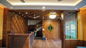 A reception area with a wooden reception desk, a staircase, and a wall-mounted sign. - Uno Premium Dalhousie (Dalhousie)