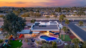 A modern hotel with a rooftop pool, outdoor seating, and a large tree in the backyard.