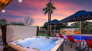 A hot tub with a poolside area, lounge chairs, and a sign for 'Moroccan Desert Oasis'.