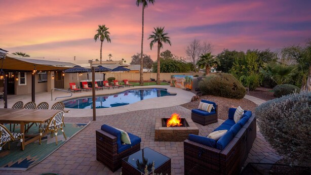 A poolside area with a fire pit, outdoor seating, and palm trees.