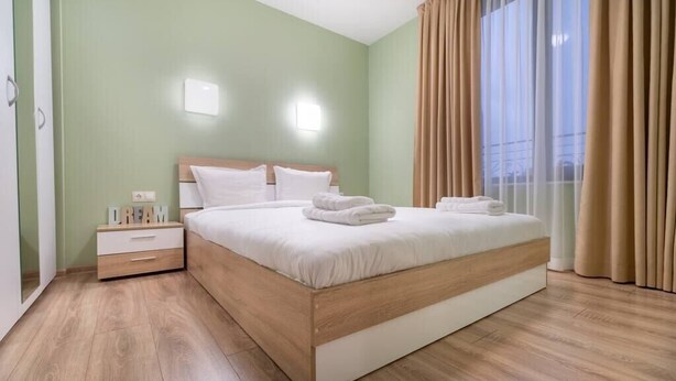 A neatly arranged bedroom with a large bed, a bedside table, and a nightstand. - City Central 1-Bed Apartments (Plovdiv)