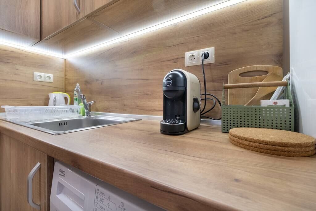 A kitchen with a coffee maker, a sink, and a green storage basket.