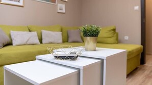 A modern living room with a green sofa, a white coffee table, and a small plant. - City Central 1-Bed Apartments (Plovdiv)