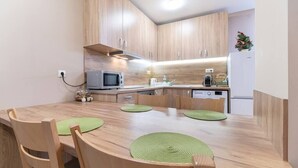 A modern kitchen with wooden cabinets, a microwave, a sink, and a refrigerator. - City Central 1-Bed Apartments (Plovdiv)