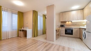 A modern kitchen with wooden cabinets, a microwave, oven, and a washing machine. - City Central 1-Bed Apartments (Plovdiv)
