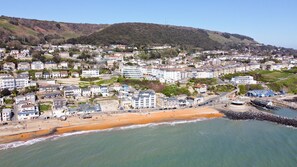 Une ville côtière avec une plage, des bâtiments et une colline en arrière-plan.