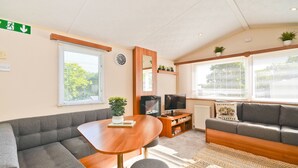En hyggelig stue med sofa, et lille bord, fjernsyn og pejs.