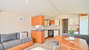En kompakt bolig med tekøkken, sofa, spisebord og lille køkkenafdeling.