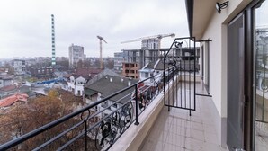 Ein Balkon mit Blick auf eine Stadtlandschaft, einschließlich Gebäude und Baukräne.