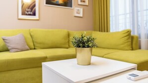 Ein hellgelbes Sofa mit einem weißen Couchtisch und einer Topfpflanze in der Mitte.