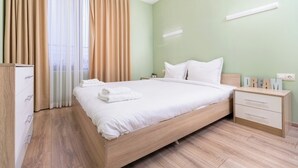 Ein ordentlich eingerichtetes Schlafzimmer mit Bett, Nachttischen, einem Kleiderschrank und einem Fenster mit Vorhängen.