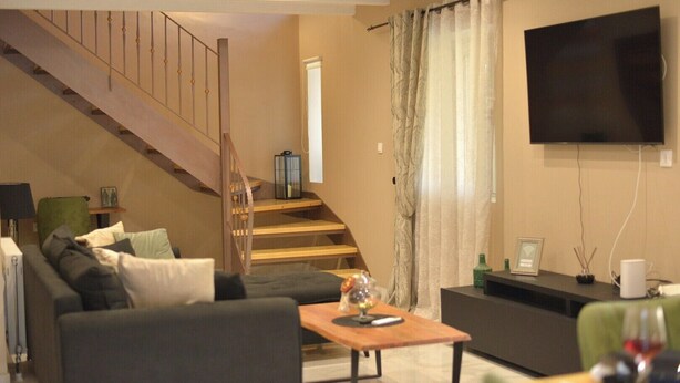 Un salon avec un escalier, un téléviseur à écran plat, une table basse et un canapé.