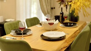 Une table à manger dressée avec des assiettes, des verres et des couverts, et un vase de fleurs en arrière-plan.