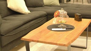 Un salon moderne avec un canapé gris foncé, une table basse en bois et un escalier en arrière-plan.