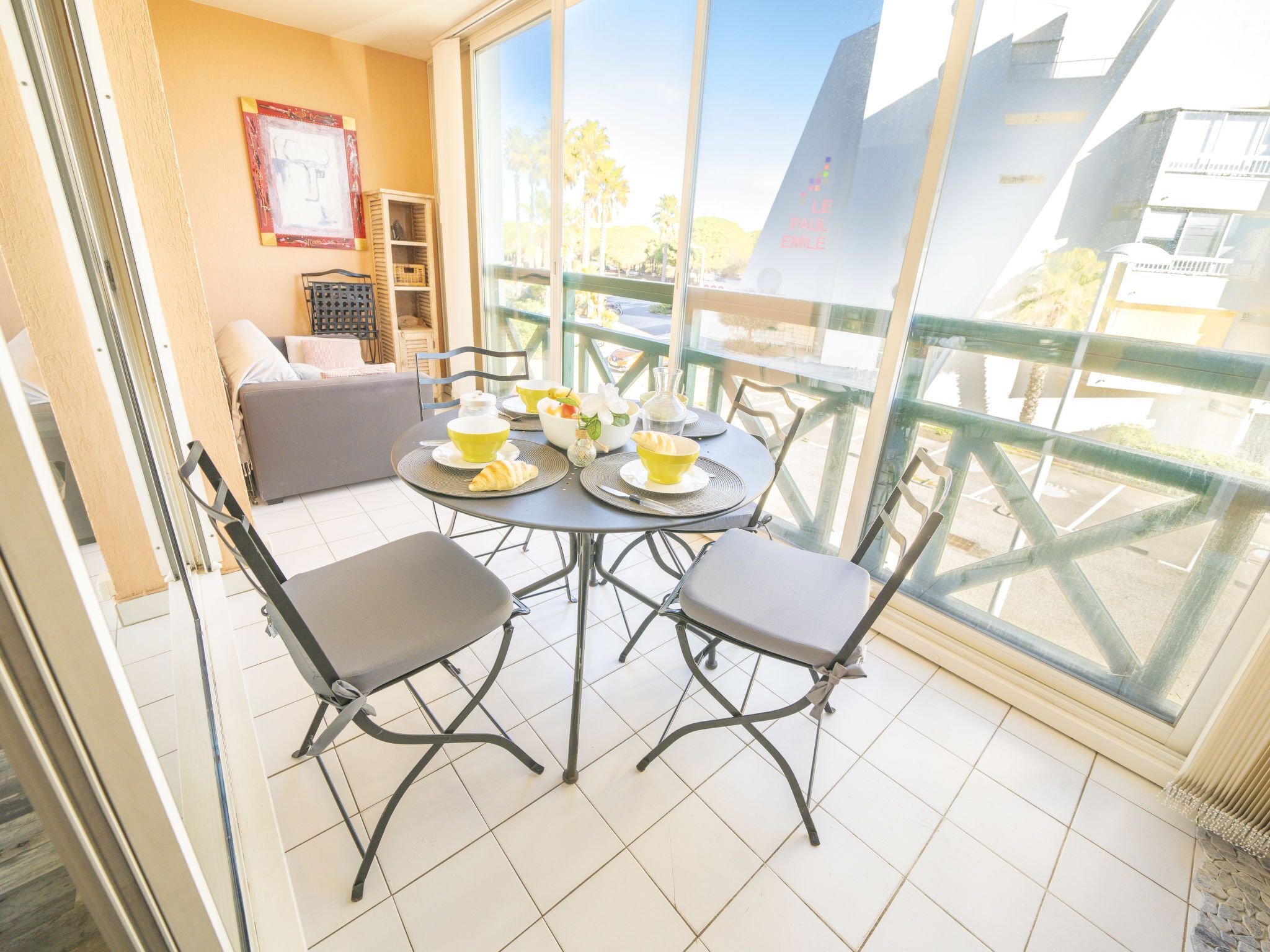 A balcony with a dining table and chairs, a sofa, and a view of the city.