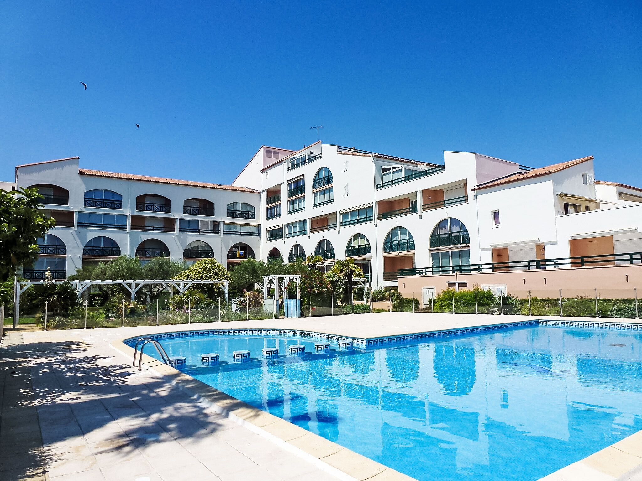 Un hôtel doté d’une piscine, de nombreux balcons et offrant une vue sur un ciel d’un bleu éclatant.