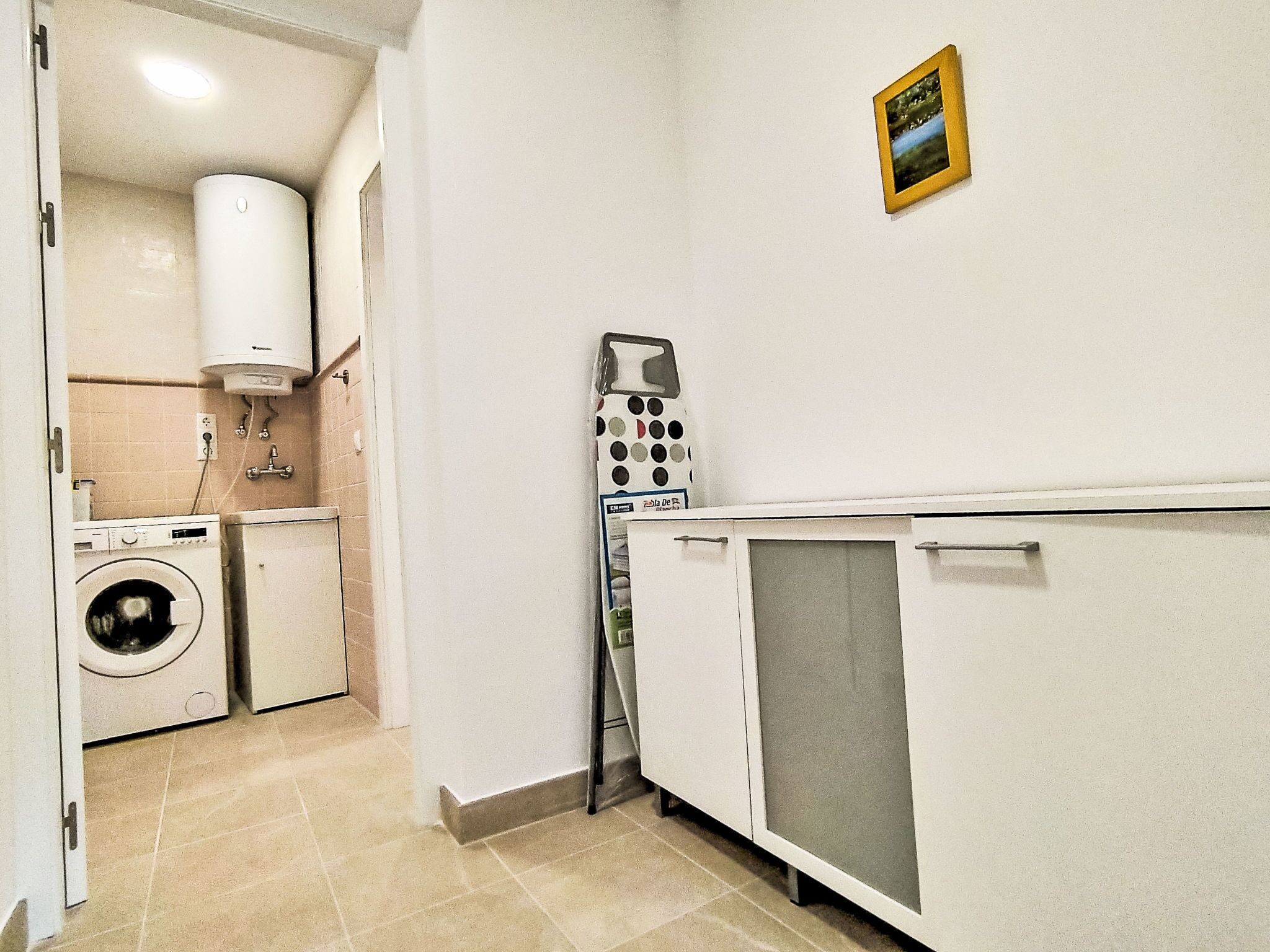 Une buanderie équipée d’un lave-linge, d’un sèche-linge et d’un étendoir.