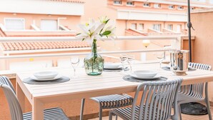 Een terras met een eettafel, een vaas met bloemen en een zonnescherm.